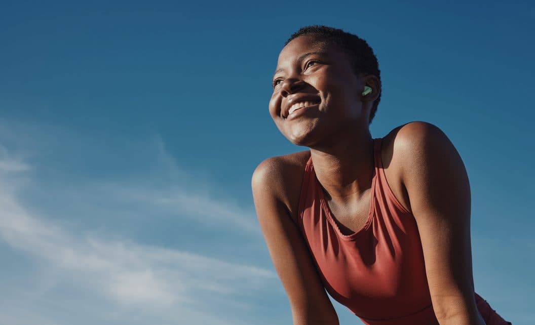 A woman smiling outdoors under a blue sky