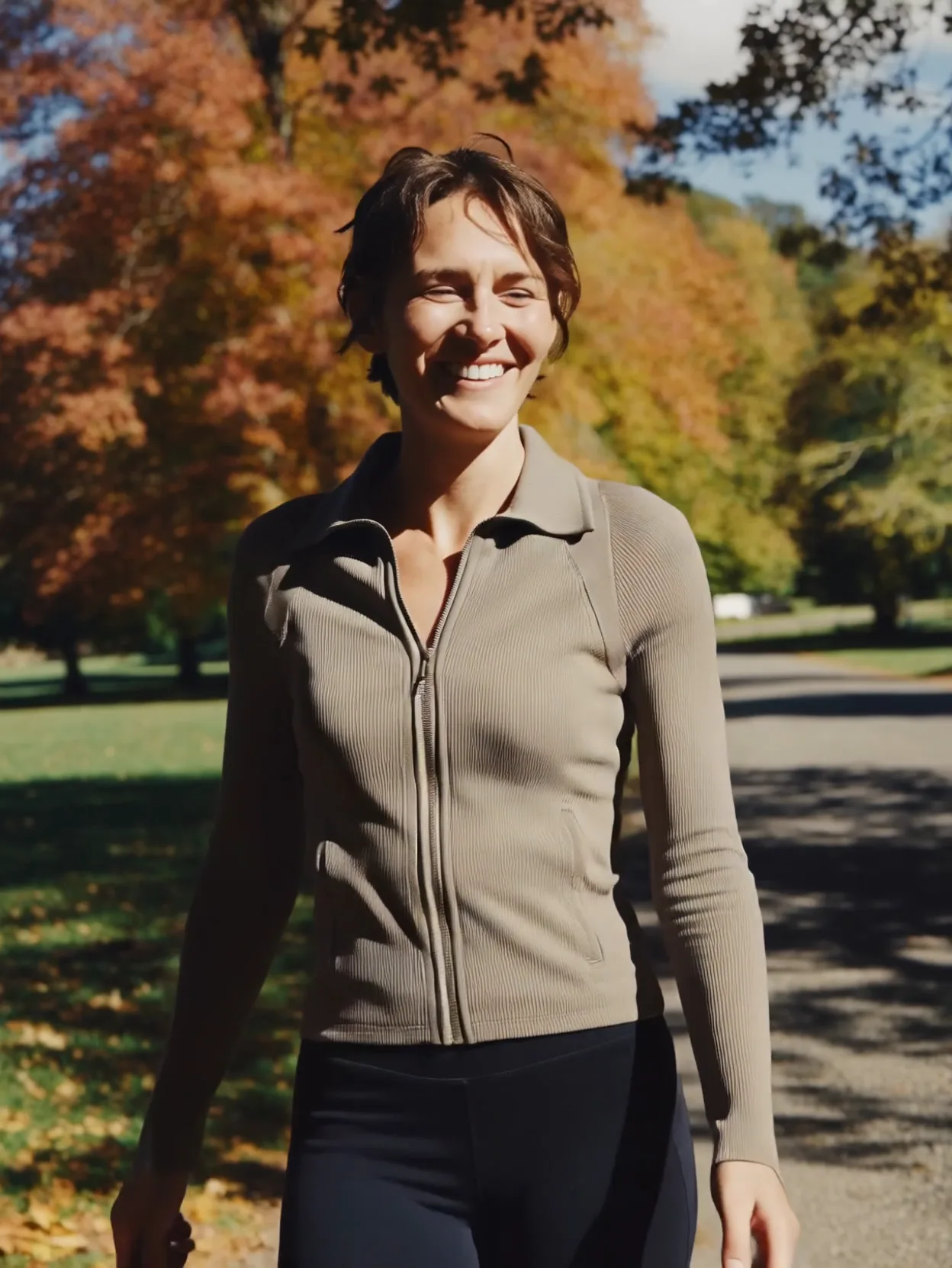 Smiling woman walking through a park on a sunny fall day